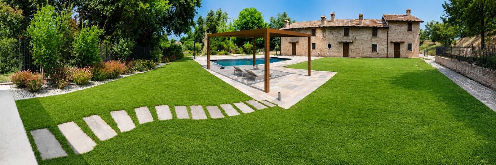 Tuscan villa with manicured lawn, stepping stones, swimming pool, and terracotta buildings surrounded by green landscape